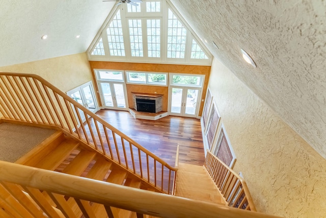 stairs with wood-type flooring, a textured ceiling, a towering ceiling, and french doors