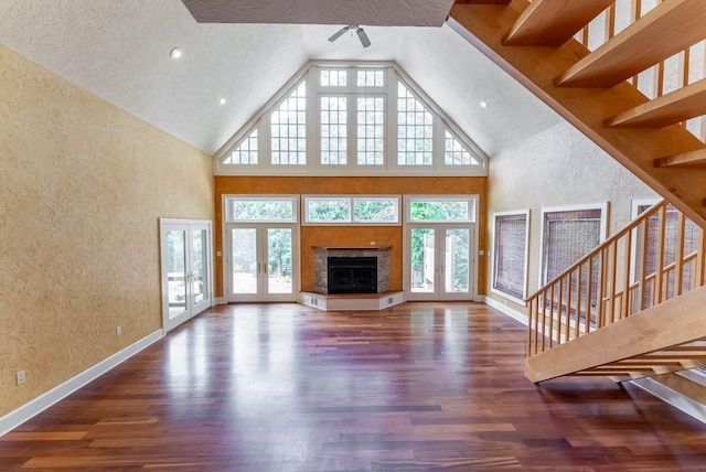 unfurnished living room with high vaulted ceiling, dark wood-type flooring, french doors, and a textured ceiling