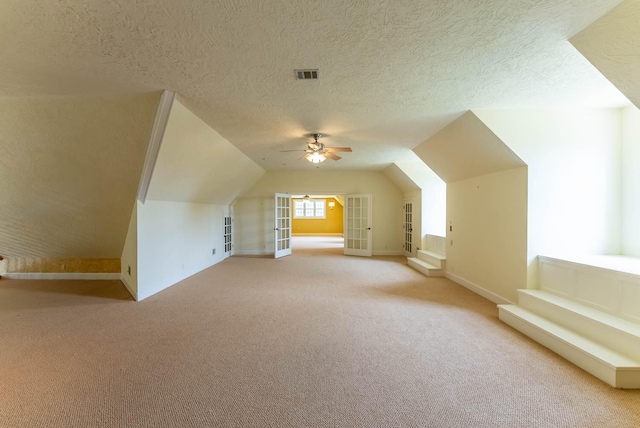 additional living space with ceiling fan, vaulted ceiling, carpet, and a textured ceiling