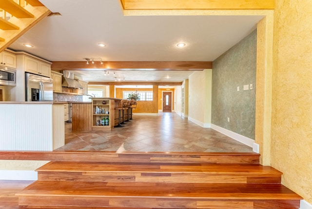 kitchen with appliances with stainless steel finishes, wall chimney exhaust hood, and rail lighting