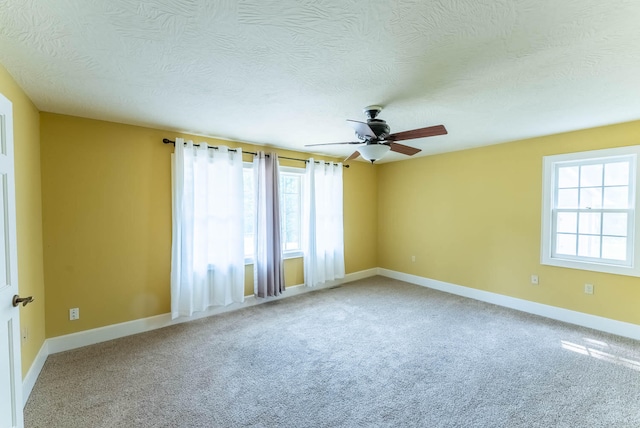 empty room featuring ceiling fan, a textured ceiling, and carpet