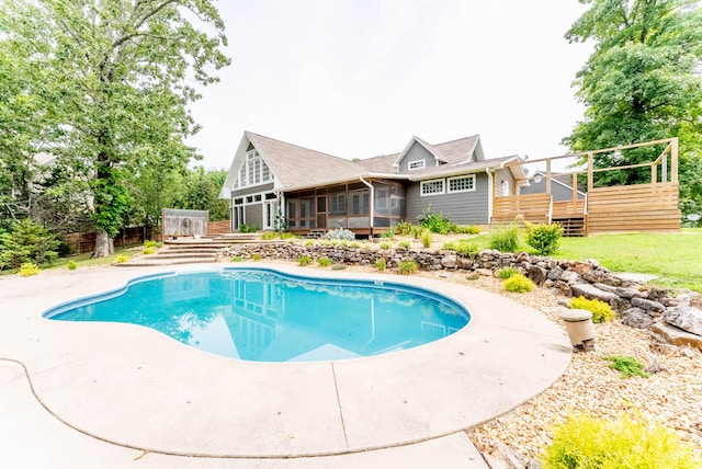 view of swimming pool featuring a sunroom and a wooden deck