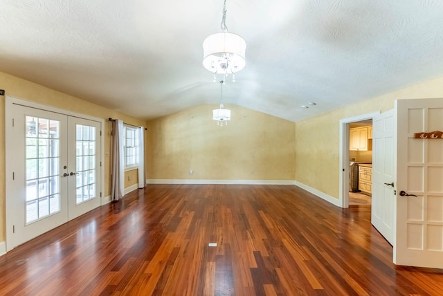 empty room with french doors, dark hardwood / wood-style floors, vaulted ceiling, and a textured ceiling