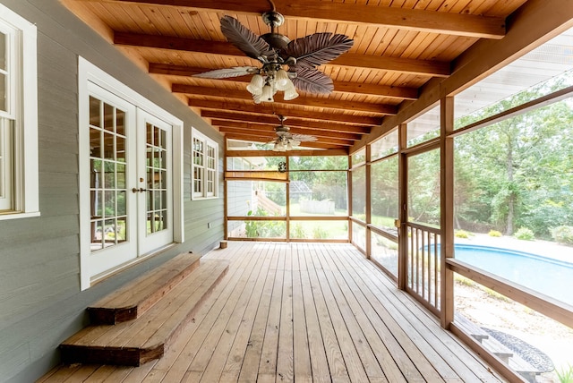 unfurnished sunroom featuring ceiling fan, a healthy amount of sunlight, vaulted ceiling with beams, and french doors