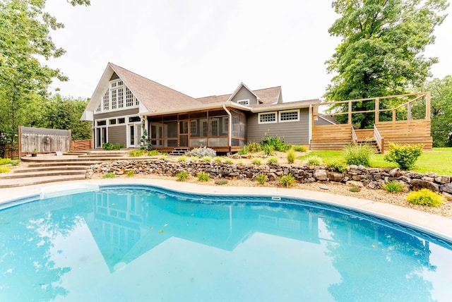 view of swimming pool featuring a sunroom and a wooden deck