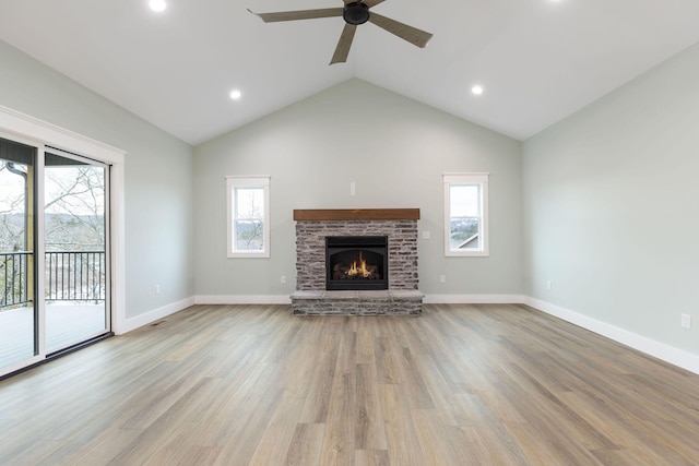 unfurnished living room featuring light hardwood / wood-style floors, ceiling fan, high vaulted ceiling, and a stone fireplace