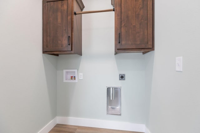 washroom with cabinets, electric dryer hookup, hookup for a washing machine, and light wood-type flooring