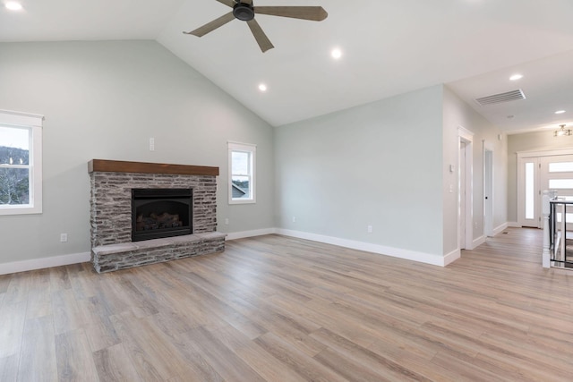 unfurnished living room featuring high vaulted ceiling, ceiling fan, a stone fireplace, and light hardwood / wood-style flooring