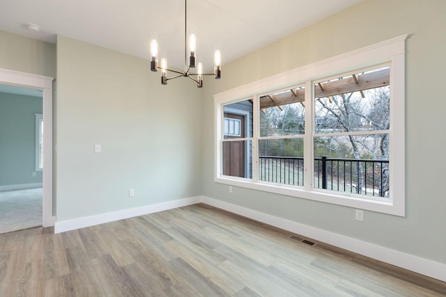 unfurnished room with a notable chandelier and light hardwood / wood-style flooring