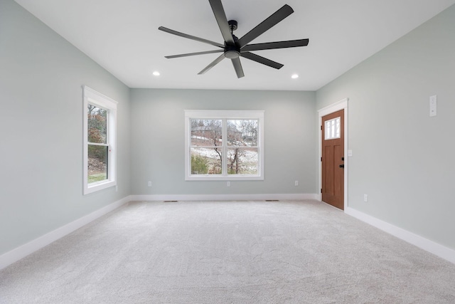 carpeted spare room featuring ceiling fan and plenty of natural light