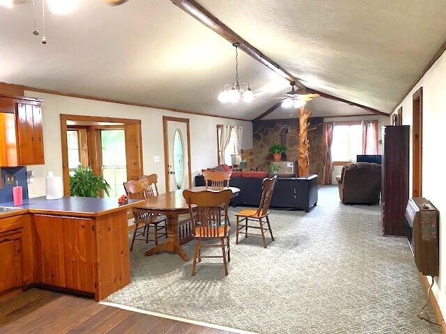 dining space featuring vaulted ceiling, heating unit, ceiling fan with notable chandelier, and hardwood / wood-style floors