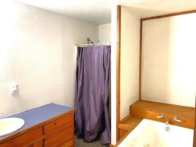 bathroom with plus walk in shower, vanity, and a textured ceiling