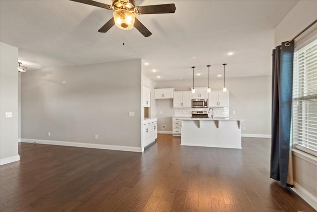 kitchen featuring an island with sink, decorative light fixtures, white cabinetry, stainless steel appliances, and a kitchen breakfast bar