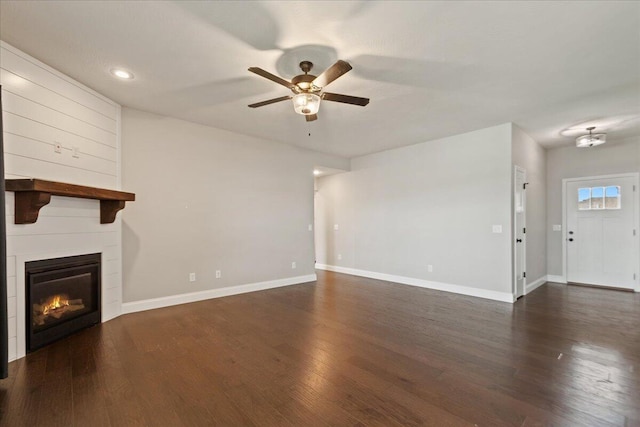 1641 N Pinnacle Ave, Nixa, MO 65714 - unfurnished living room featuring a ceiling fan, baseboards, a large fireplace, and dark wood-type flooring