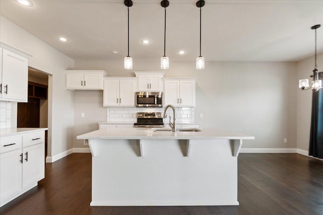 kitchen with an island with sink, sink, decorative light fixtures, white cabinetry, and stainless steel appliances