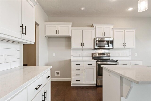 1641 N Pinnacle Ave, Nixa, MO 65714 - kitchen featuring stainless steel appliances, dark wood-type flooring, light stone countertops, tasteful backsplash, and white cabinetry