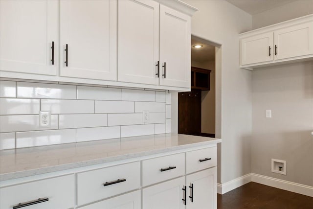 kitchen featuring dark wood-type flooring, light stone countertops, white cabinetry, and backsplash