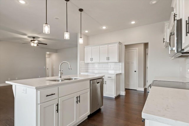 kitchen with stainless steel appliances, dark wood-type flooring, sink, white cabinetry, and a center island with sink