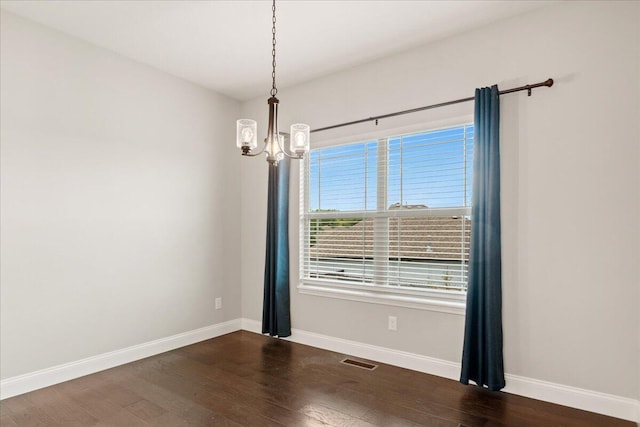 spare room featuring dark hardwood / wood-style floors and a chandelier