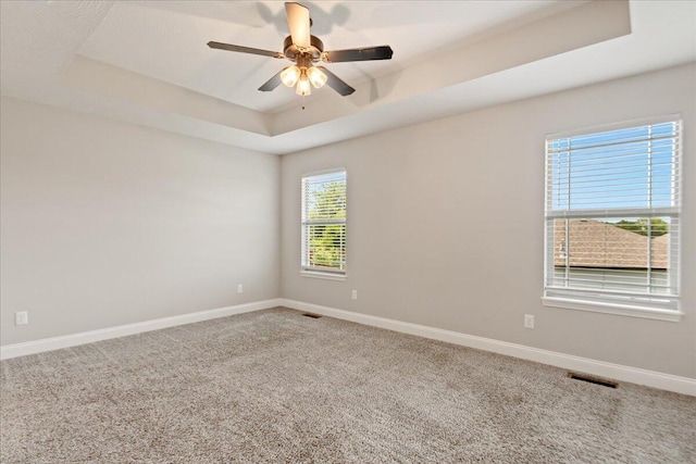 empty room featuring ceiling fan, a tray ceiling, and carpet flooring