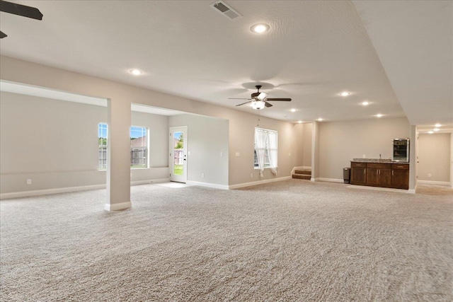 unfurnished living room featuring light carpet and ceiling fan