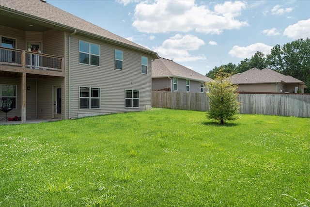 rear view of house featuring a patio, a yard, and a balcony