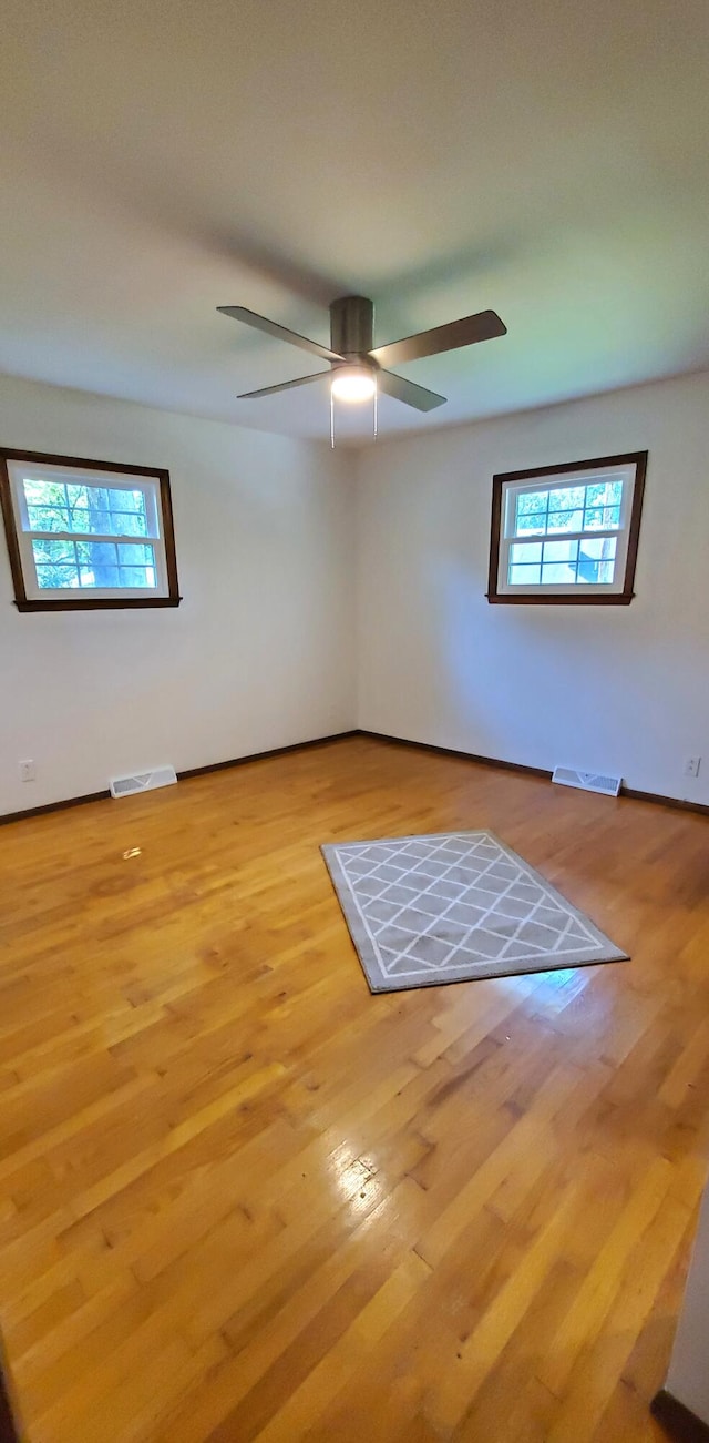 empty room with ceiling fan and light hardwood / wood-style flooring