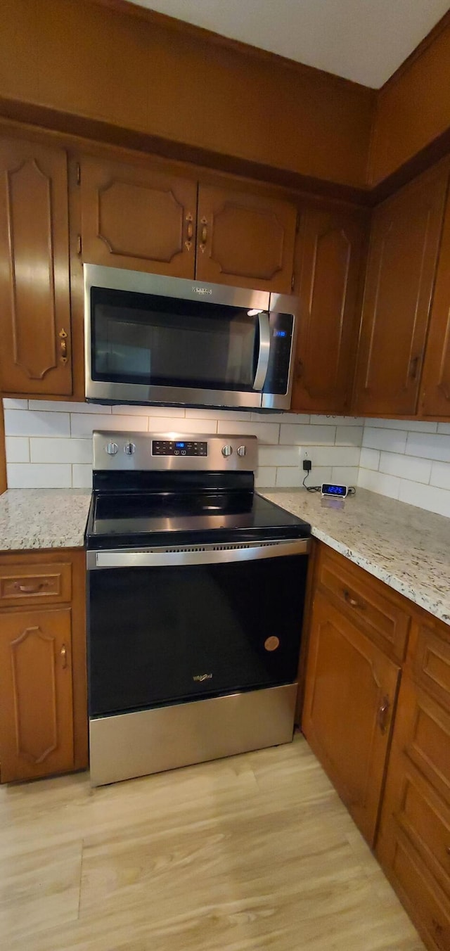 kitchen featuring appliances with stainless steel finishes, light stone counters, and backsplash