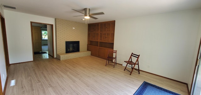 living room featuring a fireplace, light wood-type flooring, and ceiling fan