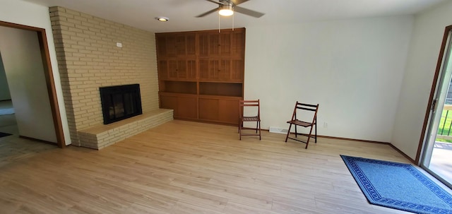 sitting room featuring a brick fireplace, light hardwood / wood-style flooring, and ceiling fan