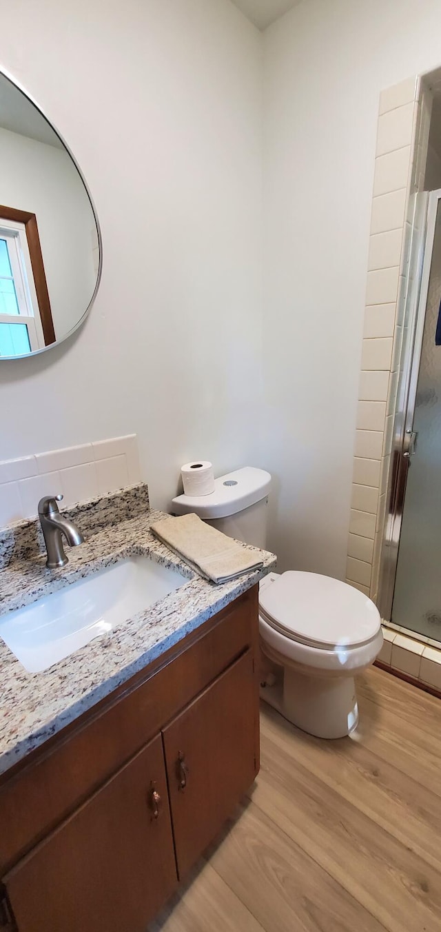 bathroom featuring hardwood / wood-style floors, walk in shower, vanity, a baseboard radiator, and toilet