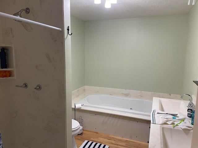 bathroom with a textured ceiling, toilet, and a bath