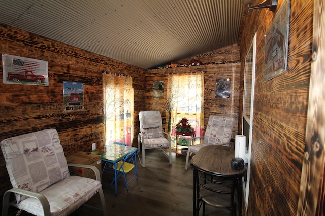 living area featuring hardwood / wood-style floors, wooden walls, and vaulted ceiling