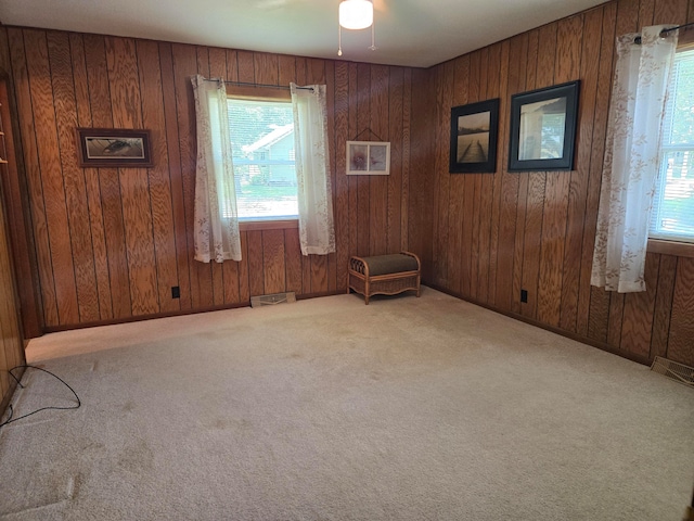 carpeted spare room with ceiling fan and wood walls