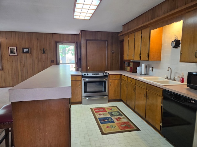 kitchen with tasteful backsplash, a breakfast bar, sink, wooden walls, and black appliances