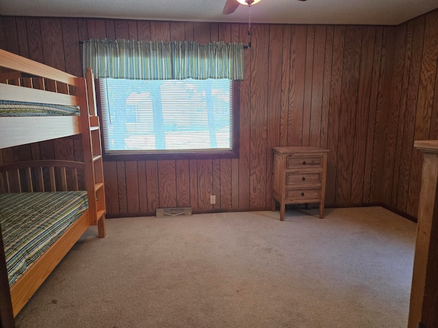 bedroom featuring wood walls, carpet, and ceiling fan