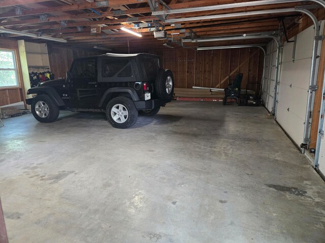 garage with a garage door opener and wood walls