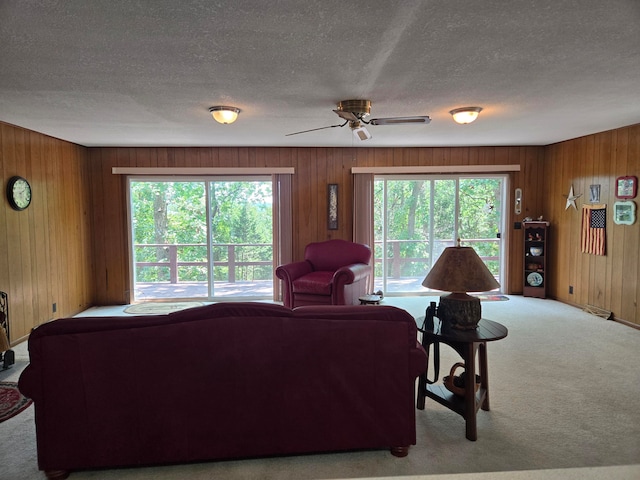 living room featuring wood walls, light carpet, and a healthy amount of sunlight