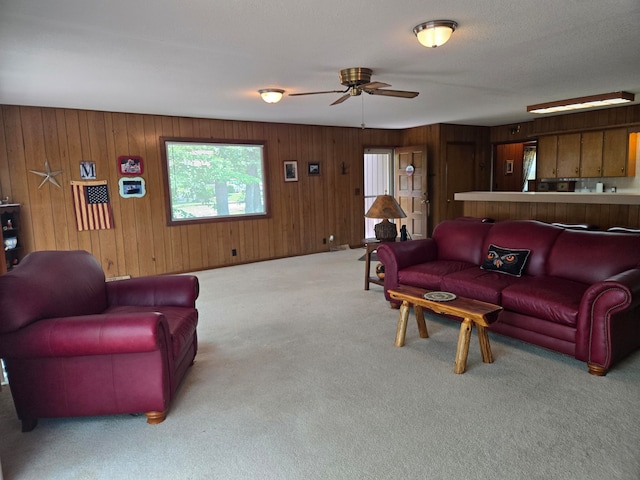 living room with light carpet, ceiling fan, and wood walls