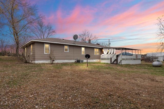 back house at dusk with a yard and central AC