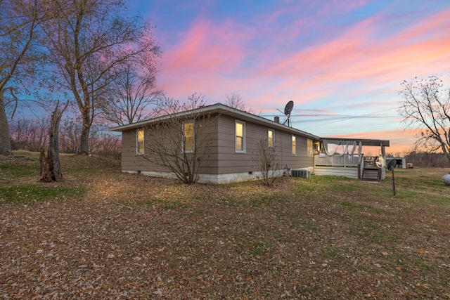 property exterior at dusk featuring central AC unit and a yard