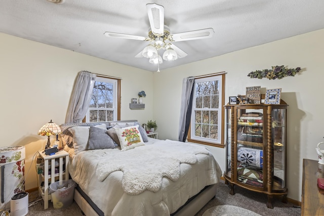 carpeted bedroom featuring ceiling fan and a textured ceiling