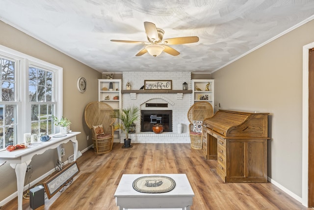 living room with ceiling fan, light hardwood / wood-style floors, crown molding, and a fireplace