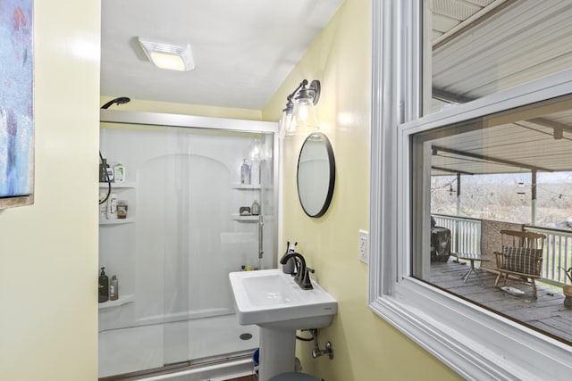 bathroom with a shower with shower door and sink