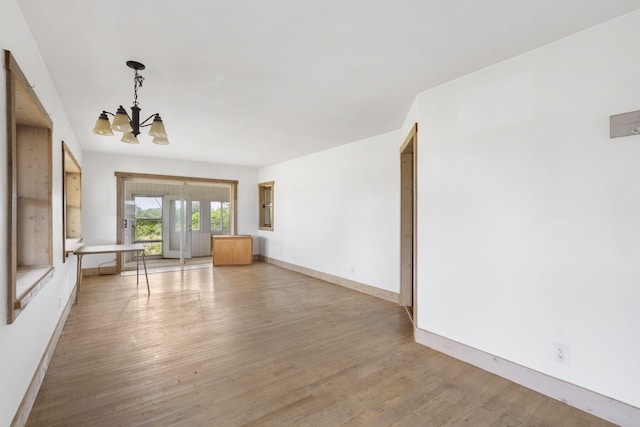 unfurnished living room with light wood-type flooring and a chandelier