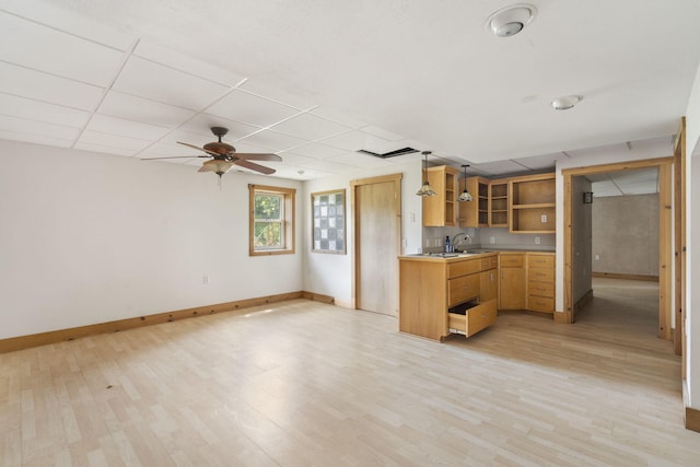 kitchen featuring ceiling fan, a paneled ceiling, sink, hanging light fixtures, and light hardwood / wood-style flooring