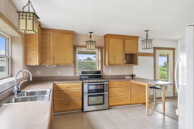 kitchen featuring plenty of natural light, stainless steel range, decorative light fixtures, and sink