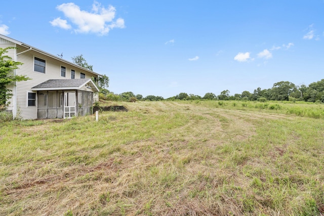 view of yard with a rural view and a sunroom