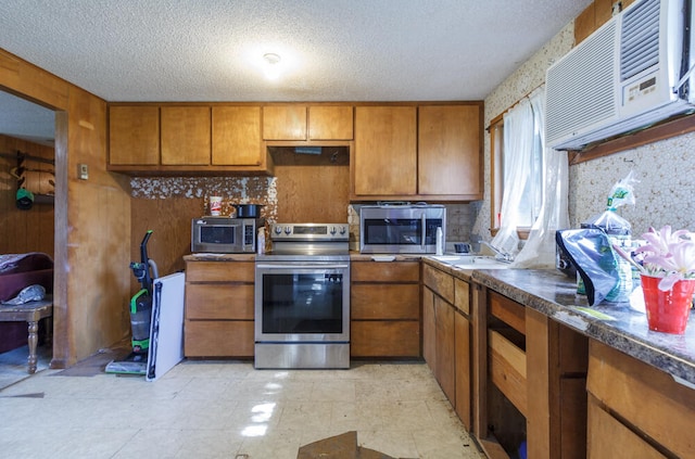 kitchen featuring stainless steel appliances, a wall unit AC, and a textured ceiling