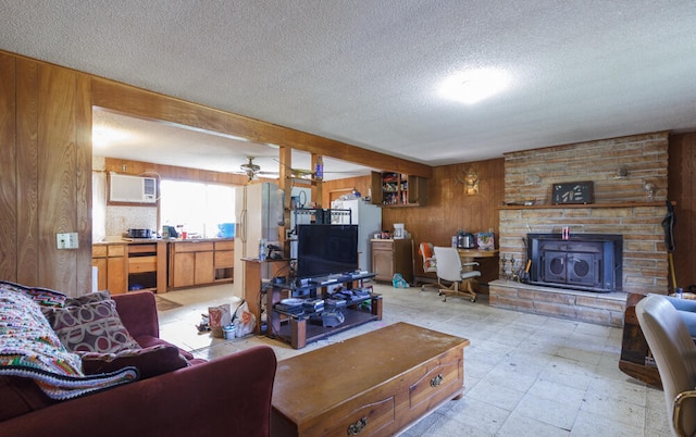 living room featuring ceiling fan, a textured ceiling, wood walls, and a wall unit AC